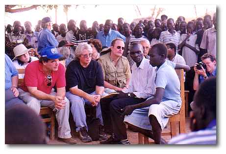 Oliver Stone (in red shirt) visits Kakuma Camp to speak with the "Lost Boys" about their refugee experience.  